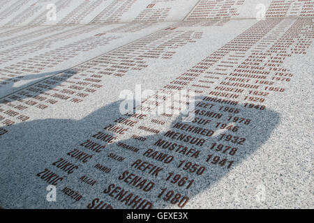 Die Menschen werfen Schatten über die Wand der Opfernamen auf dem Srebrenica Potocari Genozid-Denkmal und Friedhof für die Opfer des 1995 Genozids im östlichsten Teil der Republika Srpska, einer Einheit von Bosnien und Herzegowina. Mehr als 8,000 bosnisch-muslimische Männer und Jungen wurden getötet, nachdem die serbische Armee am 10-11. Juli 1995 trotz der Anwesenheit von UN-Friedenstruppen Srebrenica, ein ausgewiesenes UN-Sicherheitsgebiet, angegriffen hatte. Stockfoto