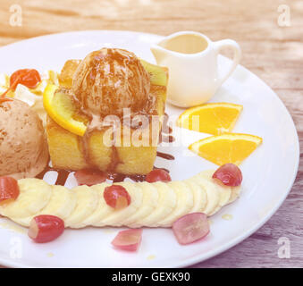 Honey Toast, bestehend aus Brot mit Honig und Eis auf Holztisch Stockfoto