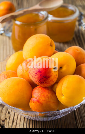Hausgemachte Bio Marillenmarmelade in Glas und Reifen Aprikosen auf rustikalen Holztisch Stockfoto