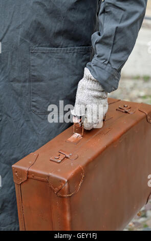 Armen wanderte mit alten Leder Koffer und der gebrochenen Handschuh während der Reise im Ausland Stockfoto