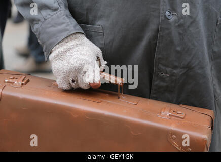 Armen Migranten mit alten Leder Koffer und der gebrochenen Handschuh bei Reisen ins Ausland Stockfoto