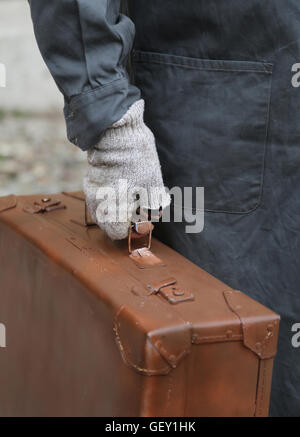 armen Einwanderer mit alten Leder Koffer und gebrochenen Handschuhe während der Reise im Ausland Stockfoto