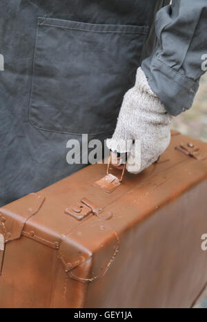 armer Mann mit alten Leder Koffer und gebrochenen Handschuhe während der Fahrt Stockfoto