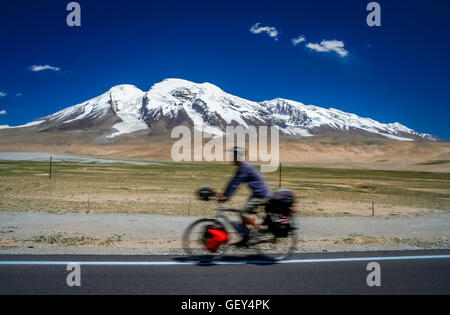 Einzigen männlichen Radfahrer auf dem Fahrrad Radfahren vor dem Muztagh Ata-Höhepunkt auf dem Karakorum Highway in China Stockfoto