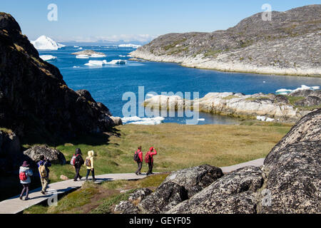 Wanderer auf Küsten-Promenade zum Inuit historische Siedlung mit Eisbergen von Ilulissat Icefjord Disko-Bucht-2016. Sermermiut Ilulissat Westgrönland Stockfoto