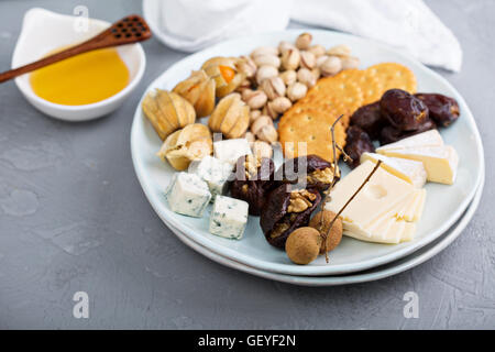 Käseplatte mit Crackern, Datteln und Nüssen Stockfoto