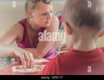 Frau auf der Suche nach Kinder malen von Bildern in Kunst Zeit im Kindergarten Stockfoto