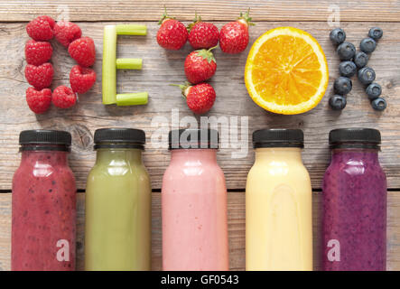 Verschiedene aromatisierte Smoothie Säfte in Flaschen mit Detox Dinkel mit Obst und Gemüse Stockfoto