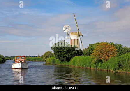 Ein Verleih Boot auf dem Fluss Ant auf den Norfolk Broads vorbei Turf Moor Entwässerung Mühle am Ludham, Norfolk, England, Vereinigtes Königreich. Stockfoto