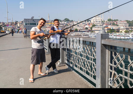 Istanbul, Türkei - 1. Juli 2016: Lächelnde junge Erwachsene Fischer am Galata-Brücke über das Goldene Horn in Istanbul, Türkei Stockfoto