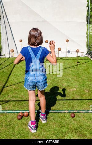 Ein Kind wirft einen Ball an Kokosnüssen auf eine traditionelle Coconut Shy, Withyham Fete, Withyham, Sussex, UK Stockfoto