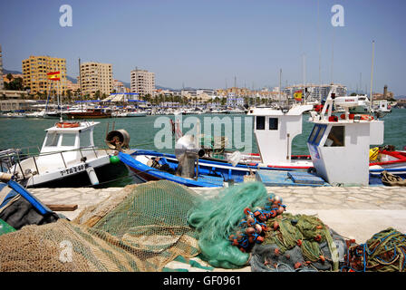 Traditionelle Fischerboote und Netze im Hafen mit Yachten und die Marina auf der Rückseite, Estepona, Provinz Malaga, Spanien. Stockfoto