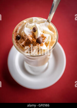 Kaffee Latte im Longdrinkglas mit Sahne, Cinnanmon und Kaffee Bohnen als Beilage Stockfoto