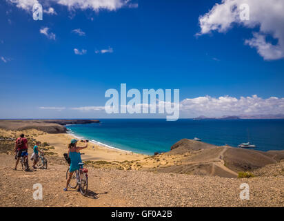 Menschen auf Fahrrädern, die den Blick auf Playa Mujeres in Lanzarote, Kanarische Inseln, Spanien. Bild 20. April 2016. Stockfoto