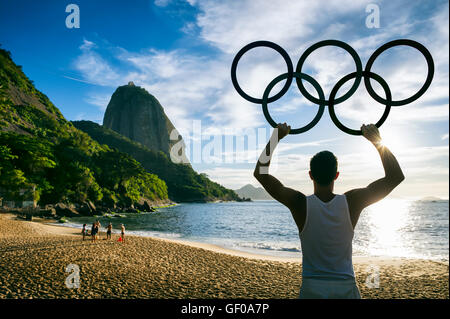 RIO DE JANEIRO - 31. Oktober 2015: Athlet hält Olympische Ringe vor Sonnenaufgang Silhouette der Zuckerhut. Stockfoto