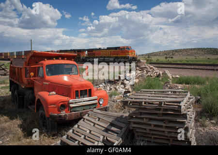 1954 internationaler Harvester-Kipper R190 mit Paletten und Zug, der in Stapeln von Holzpaletten vorbeifährt und ein Güterzug vorbeifährt Stockfoto