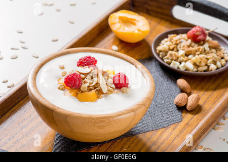 Joghurt mit frischen Früchten, Himbeeren, Müsli und Mandeln auf Tablett. Gesundes Frühstück-Konzept. Selektiven Fokus Stockfoto