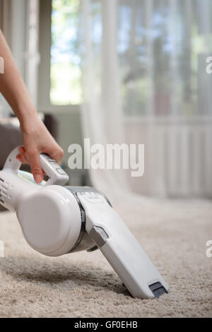 Frau schnurlosen Handstaubsauger Teppich Reinigung Stockfoto