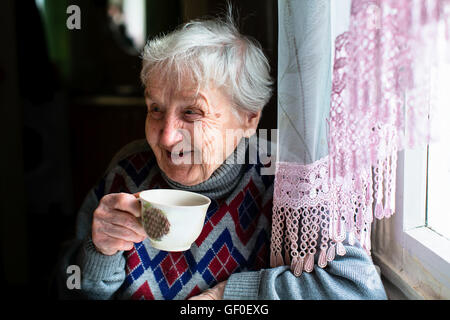 Glücklich Seniorin Porträt sitzen am Tisch und trinken Tee. Stockfoto