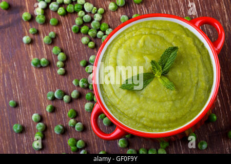 Schüssel mit gesunde grüne Erbsensuppe auf rustikalen Holztisch Stockfoto