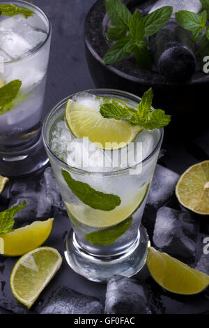 Mojito cocktail mit Limetten und Glas auf schwarzem Stein Stockfoto