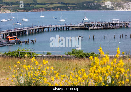 Auf der Suche nach unten über Swanage Pier mit Boote ankern in der Bucht und Dorset Küste im Juli Stockfoto