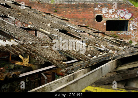 Beschädigte gewellten Asbest Dach auf verlassenen Industriegebäude. Stockfoto
