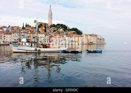 Angelboot/Fischerboot kehrt in den frühen Morgenstunden zum Hafen von Rovinj mit der Altstadt im Hintergrund. Stockfoto