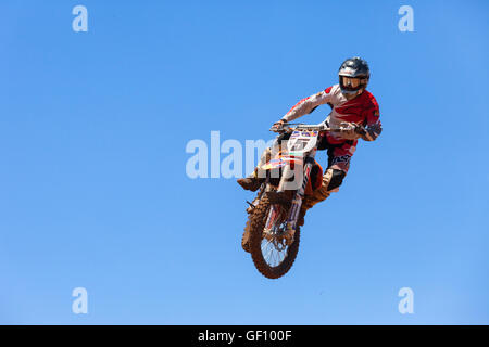 Motocross-Fahrer und Bike clearing eine Tischplatte zu springen, während die letzte Wärme des Rennens Stockfoto