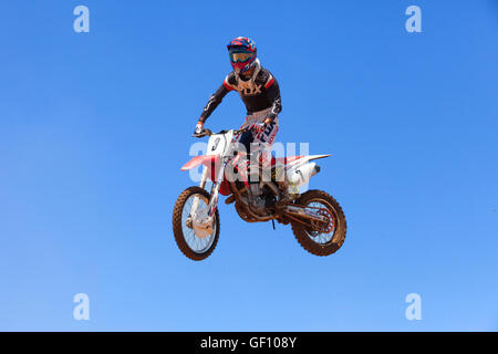 Motocross-Fahrer und Bike clearing eine Tischplatte zu springen, während die letzte Wärme des Rennens Stockfoto