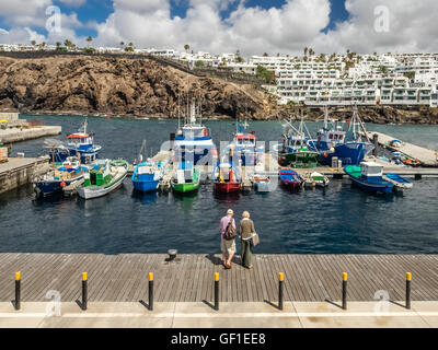 Älteres Ehepaar auf einem Holzdeck im Hafen von Puerto del Carmen in Lanzarote Kanarische Inseln, Spanien. Foto von April 201 Stockfoto