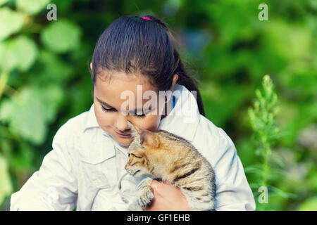Niedliche trauriges Mädchen umarmt eine Katze im Garten Stockfoto