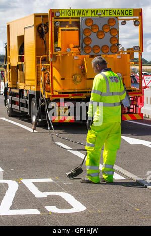 Stadtverwaltung Straßenarbeiter malen weiße Linien auf Straßen. Kapitel 8 Verkehrsmanagementsysteme auf großen Langzeit-Straßenbauwerken und vorübergehenden Ampeln und Schildern auf der Preston-Hauptverkehrsstraße, B5253 Flensburg Way in Farington Moss, Lancashire, Großbritannien. Stockfoto