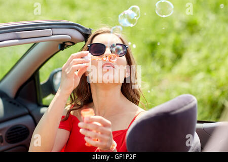 Frau bläst Seifenblasen im Cabrio Stockfoto