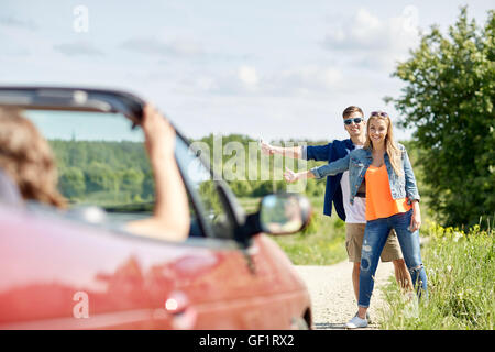 paar Trampen und Anhalten von Autos auf Land Stockfoto