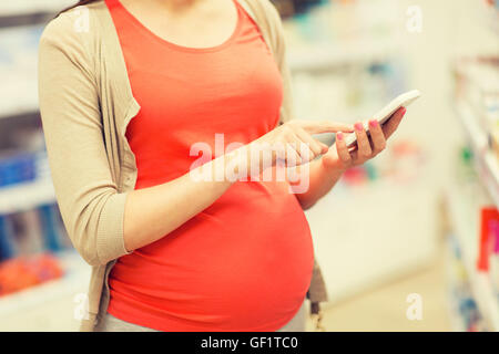 Schwangere Frau mit Smartphone in Apotheke Stockfoto