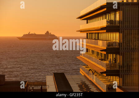 Ein Kreuzfahrtschiff verlässt Cádiz Bucht bei Sonnenuntergang, während Menschen die Aussicht von der Terrasse des Hotels genießen "Hotel Parador de Cádiz Atla Stockfoto