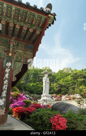 Seite des Gebäudes, üppige Vegetation und die große Statue von Maitreya Buddha in Bongeunsa-Tempel in Gangnam, Seoul, Südkorea. Stockfoto