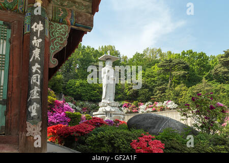 Seite des Gebäudes, üppige Vegetation und die große Statue von Maitreya Buddha in Bongeunsa-Tempel in Gangnam, Seoul, Südkorea. Stockfoto