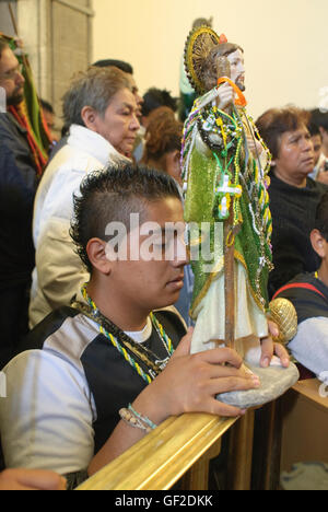 Anbeter mit Statuen und andere Artikel der Hingabe an Saint Jude Thaddeus, helfen bei einer Messe in Mexiko-Stadt. Stockfoto