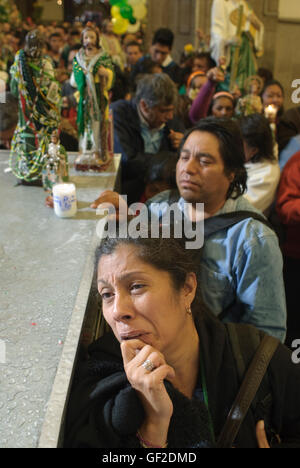 Anbeter mit Statuen und andere Artikel der Hingabe an Saint Jude Thaddeus, Schutzpatron der verlorenen Ursachen helfen bei einer Messe. Stockfoto