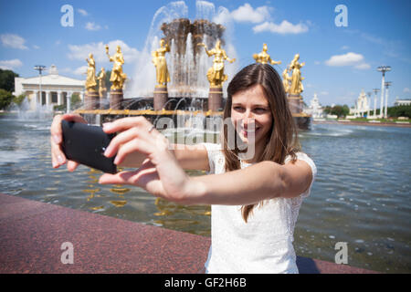 Schöne, Brünette Frau lächelnd nehmen Sie ein Bild von sich selbst mit einem Smartphone. Selfie, im freien Stockfoto