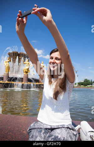 Schöne, Brünette Frau lächelnd nehmen Sie ein Bild von sich selbst mit einem Smartphone. Selfie, im freien Stockfoto