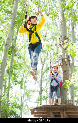 Glückliche chinesische Kinder spielen im Tree Top Adventure park Stockfoto