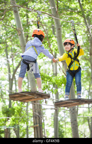 Glückliche chinesische Kinder spielen im Tree Top Adventure park Stockfoto