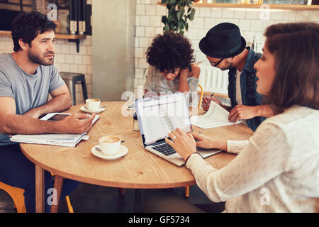 Team von kreativen Menschen sitzen in einem Café mit einigen Dokumenten und Laptop. Junge Männer und Frauen in Coffee-Shop für Business meetin Stockfoto
