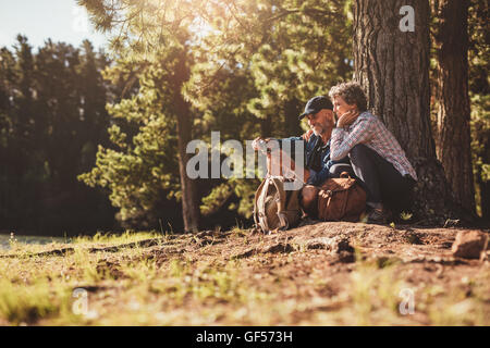 Älteres Paar auf der Suche nach dem Weg mit Hilfe eines Kompasses lächelnd. Älteres Paar im Wald wandern. Stockfoto