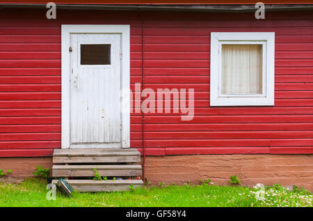 Kleine weiße Tür und Fenster in roten ländlichen Holzwand, Foto Hintergrundtextur geschlossen. Skandinavischen Stil Stockfoto