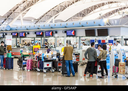 Japan, Kansai Airport, KIX. Interieur, Terminal 1. International check-in. Warteschlangen der Asiatischen Personen mit Gepäck Trolleys, in der an den Arbeitsplätzen zu überprüfen. Stockfoto