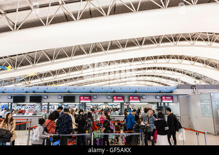 Japan, Kansai Airport, KIX. Interieur, Terminal 1. International check-in. Warteschlangen der Asiatischen Personen mit Gepäck Trolleys, in der an den Arbeitsplätzen zu überprüfen. Stockfoto